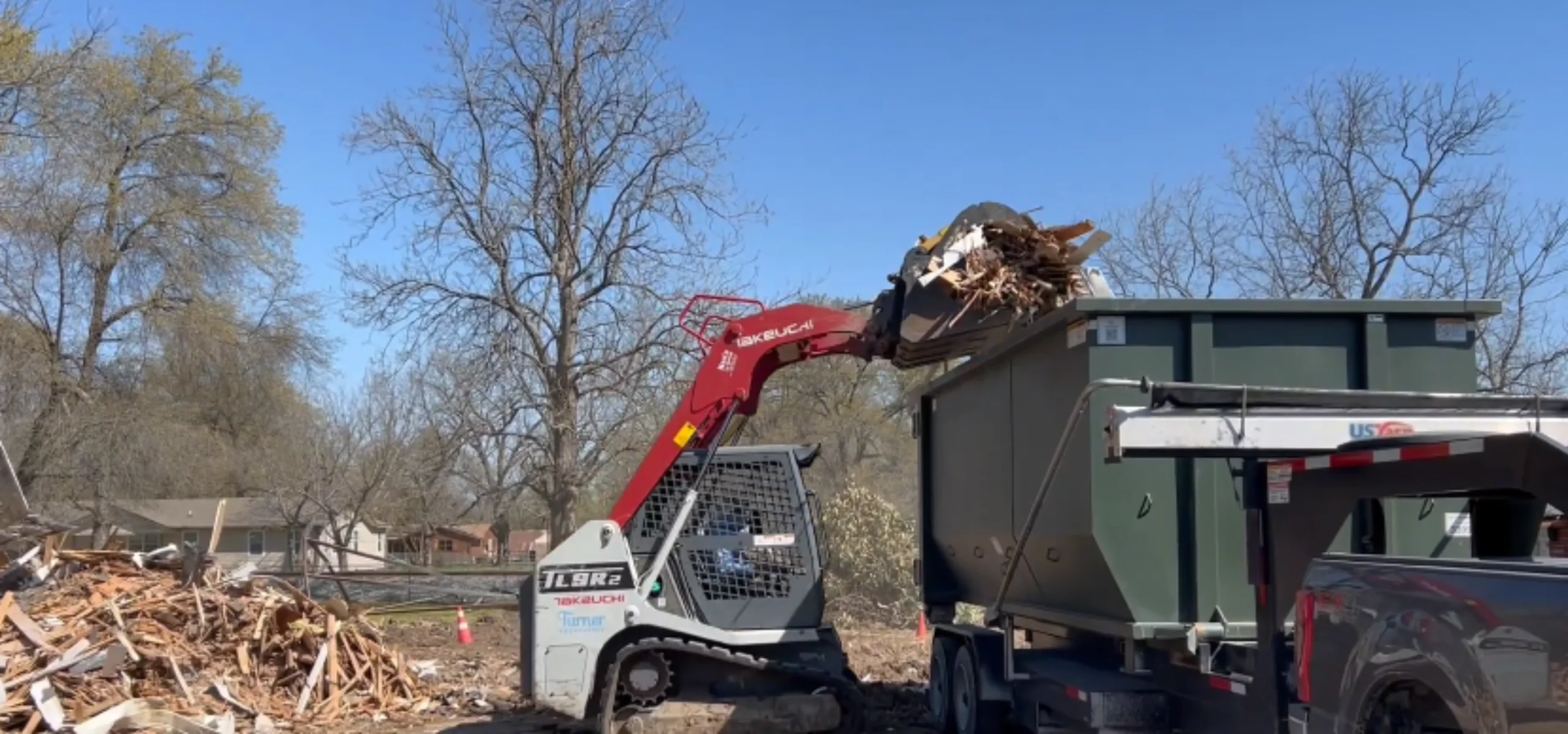 Skid steer loading demolition debris into a large roll-off dumpster — 40 yard commercial job in Owensboro KY